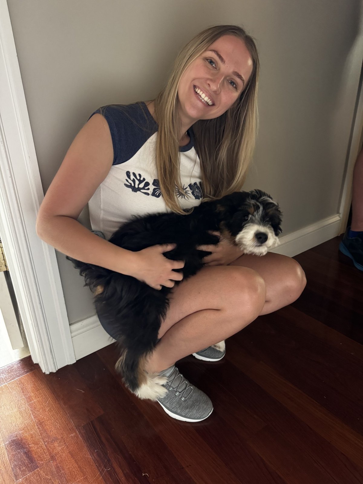 A pet sitter holding a black-and-white puppy